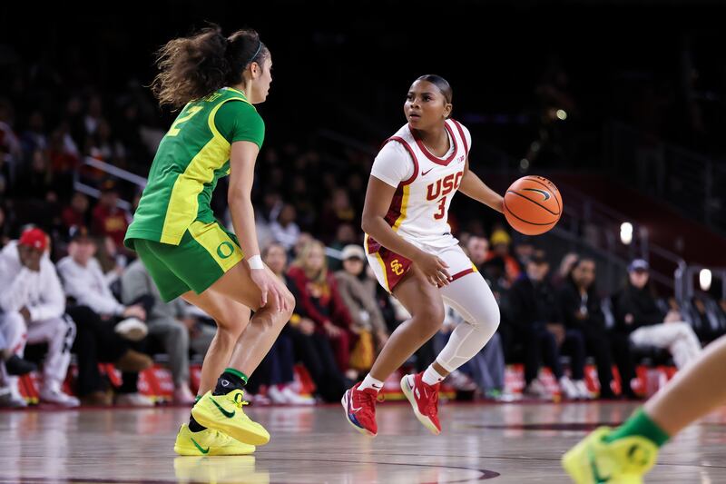 Londynn Jones (3) in the air with the basketball closely followed by an Oregon defender.