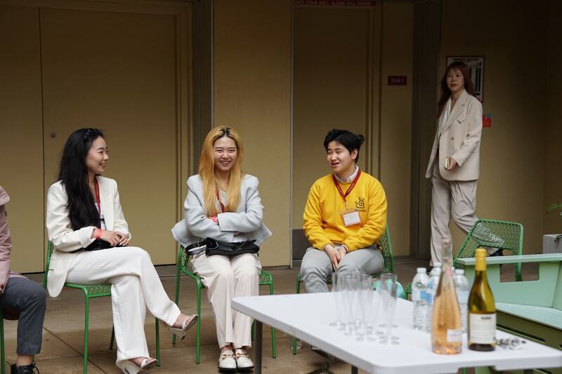 Photo of three women sitting in chairs in front of a table