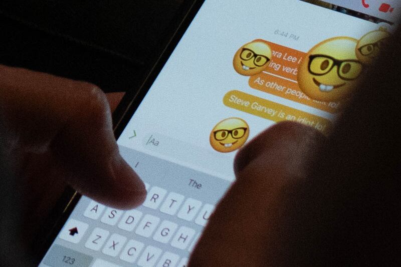 The phone of a debate attendee sending a message that reads “Steve Garvey is an idiot lol” as bucktooth emojis wearing glasses fill their screen in the middle of the debate.