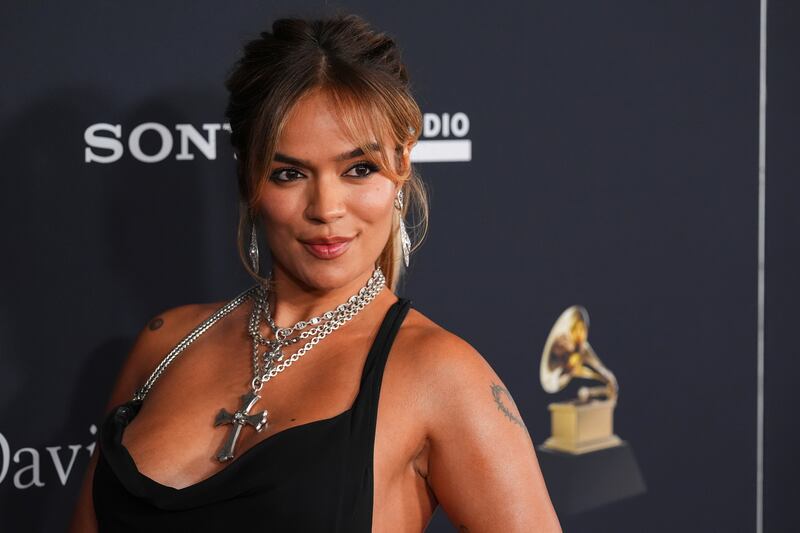 Photo of a woman in a black dress standing in front of a sign that says Sony with the Grammmys logo.