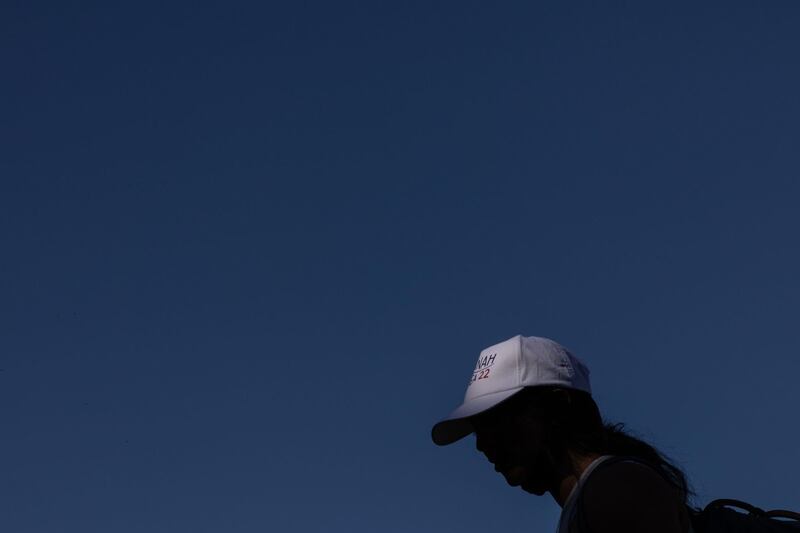Krishnan in a baseball hat against a blue sky.