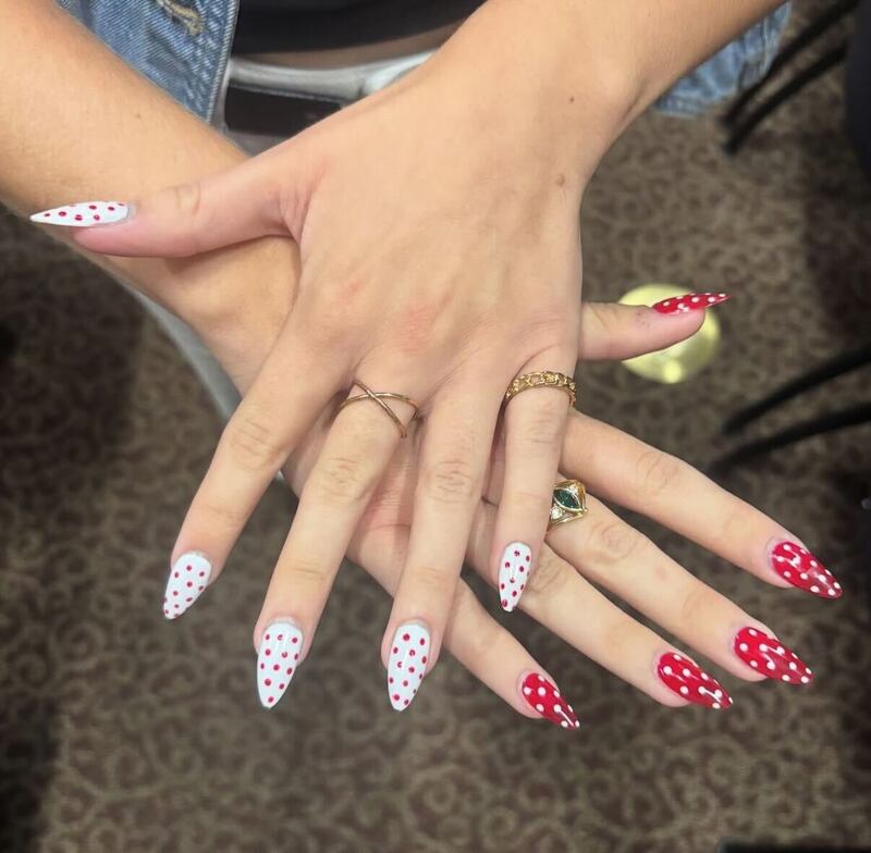 Two hands with a custom polka-dot set of nails, red and white.