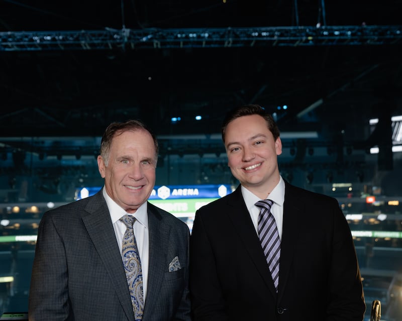John Kelly and Josh Schaefer pose and smile together at Crypto.com Arena. Both wear suits.