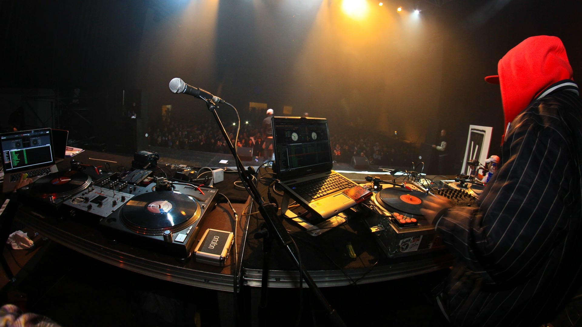 A DJ plays hip-hop music for a packed music venue.