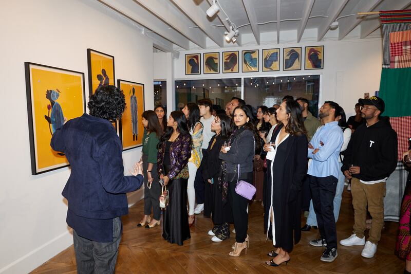 Photo of a man speaking to a large group in front of paintings
