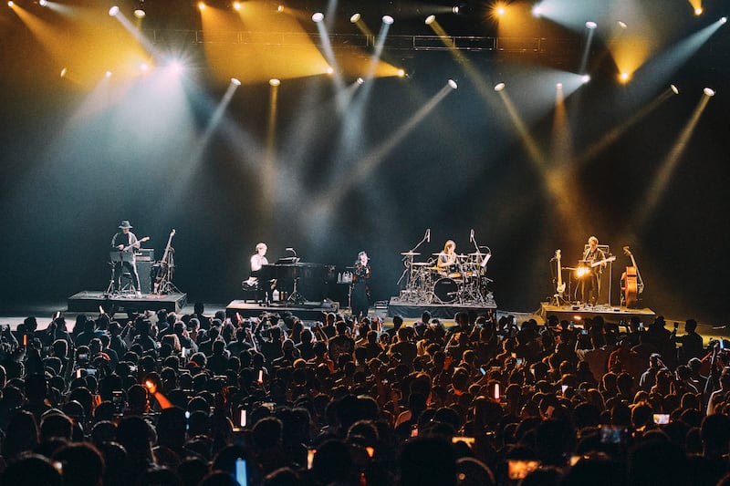 Audience with light sticks watches mizuki performs with Sawano and the band.