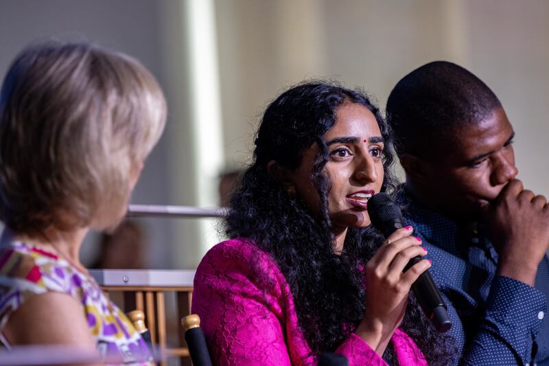 Photo of student filmmaker holding a microphone, speaking on a panel.