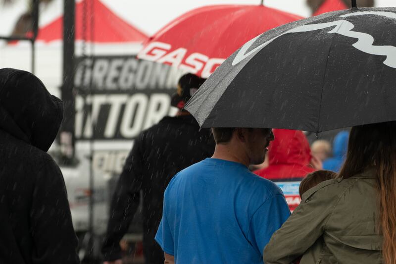 Fans huddle beneath umbrellas as a brief rainstorm passes through Southern California.