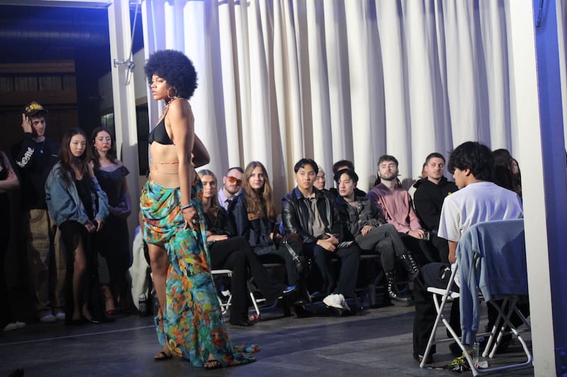 A model walks the runway with a bra top and a long skirt
