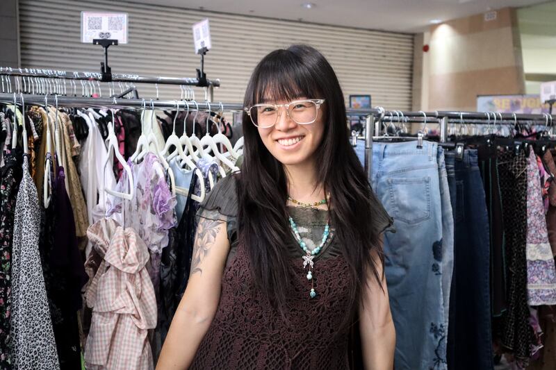 Person smiling in front of clothes