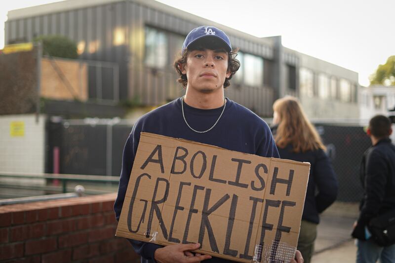 A protestor with an 'Abolish Greek Life' sign