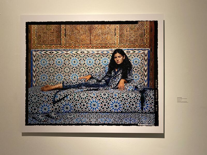 A photo of an artwork that features a woman on a couch that has an ornate pattern.