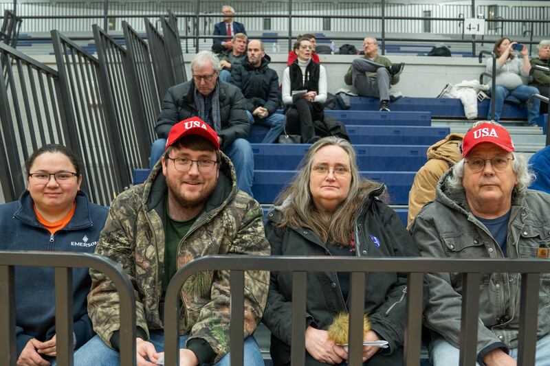 A family sits together on bleachers at the caucus.