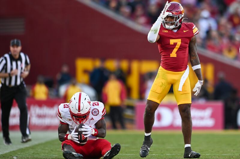 A photo of Kamari Ramsey, wearing a red USC throwback jersey, standing over a Nebraska player after a tackle.