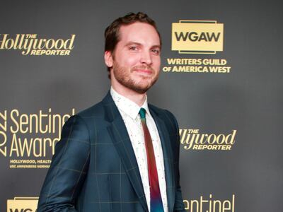 A photo of Schleicher in a navy suit smiling and posing on the red carpet.