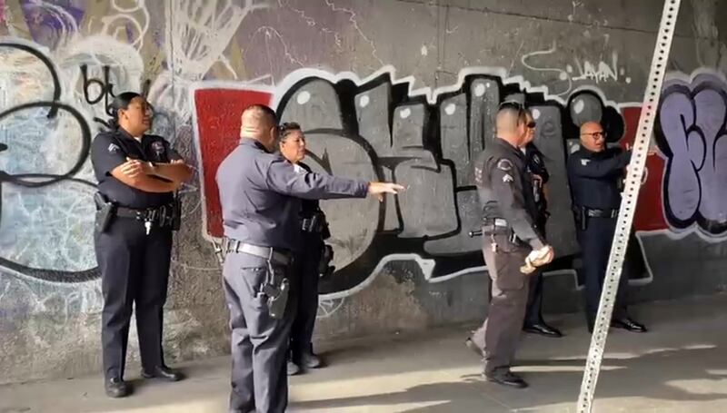 Photo of six LAPD officers in front of a graffiti-covered wall.
