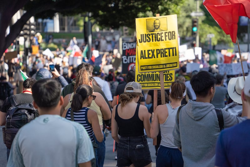 A protester holds a yellow sign reading "Justice for Alex Pretti" among thousands of protesters.