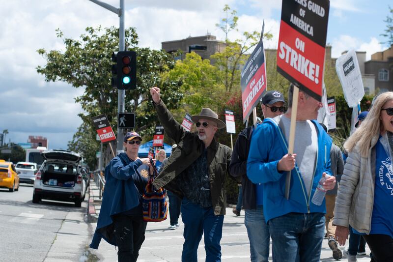 A picketer raises his fist as cars honk in support of the strike.