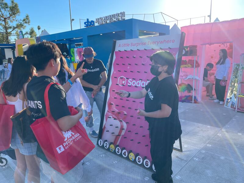 Photo of a person in black handing a disc to another person in front of a pink board with pegs