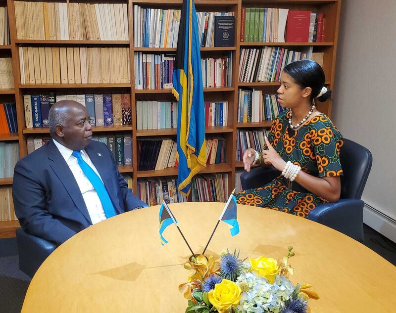 A young woman meeting Prime Minister Philip Davis of the Bahamas at a table.