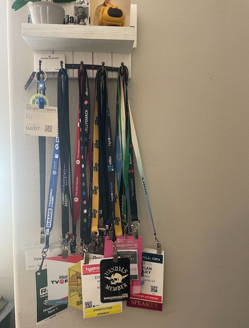 Different neck passes hang on a set of five white hooks.