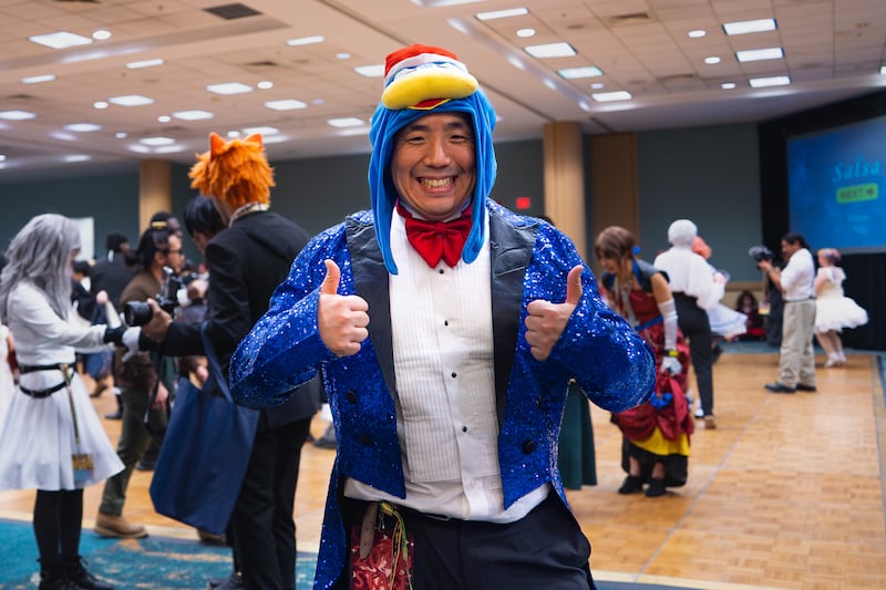 Yamaguchi in a blue sequined tuxedo and a Donpen hood, with both thumbs up for the picture.