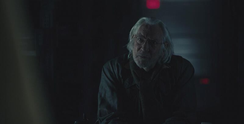 A man with long, grey hair looks concerned.