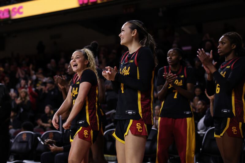 A handful of Trojans celebrate on the sideline.