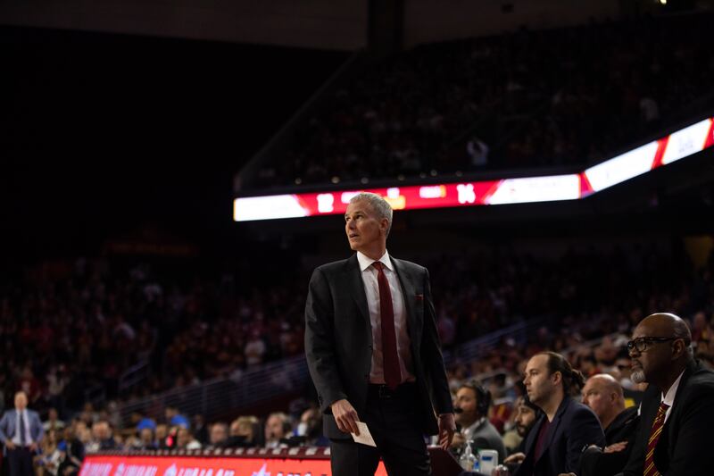 USC head coach Andy Enfield looks on during the USC-UCLA men's basketball game. He is wearing a suit with a cardinal tie.