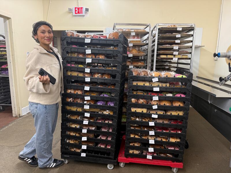 Photo of a woman standing next to stacks of baked sweet bread.