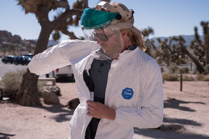 Nolan Graham, a volunteer climbing steward with Friends of Joshua Tree, puts on protective gear as he prepares to clean the graffiti. (Photo by Michael Chow)