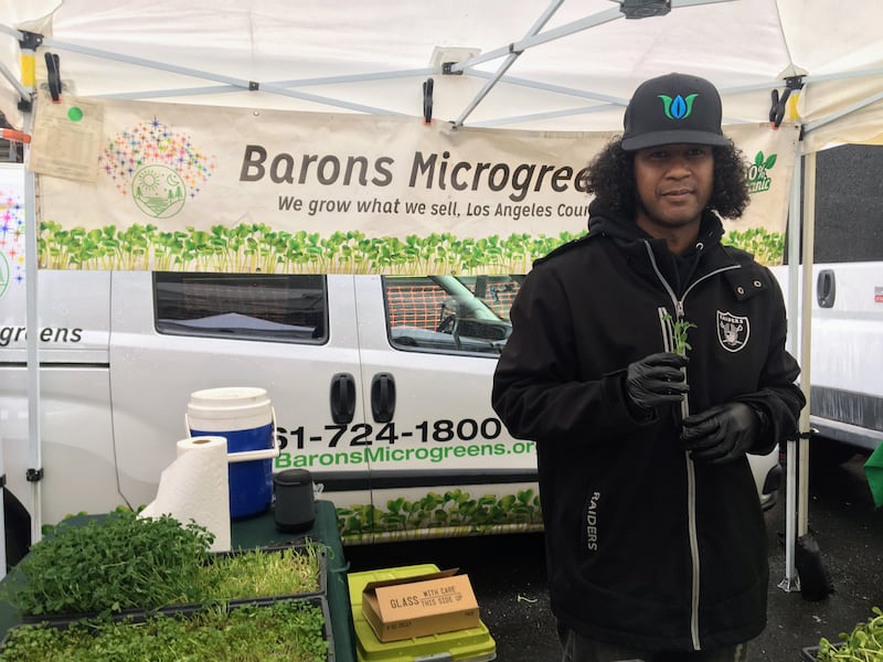 Jarvez Turnage poses with a microgreen outside his farmers' market stall in Downtown Los Angeles.