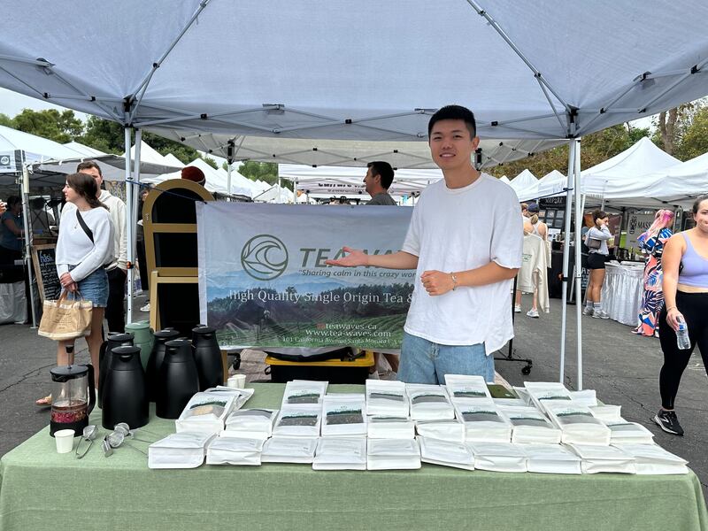 Photo of young man standing next to a tea booth.