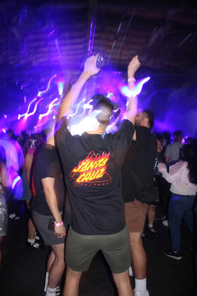 Blue and purple strobe lights wave over a man dancing along.
