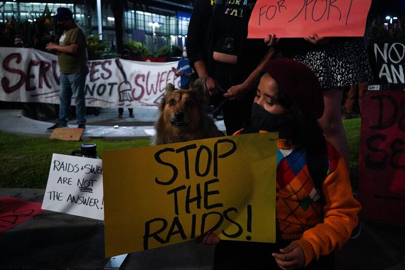 A protester holds a sign with the message: "Stop the raids!"