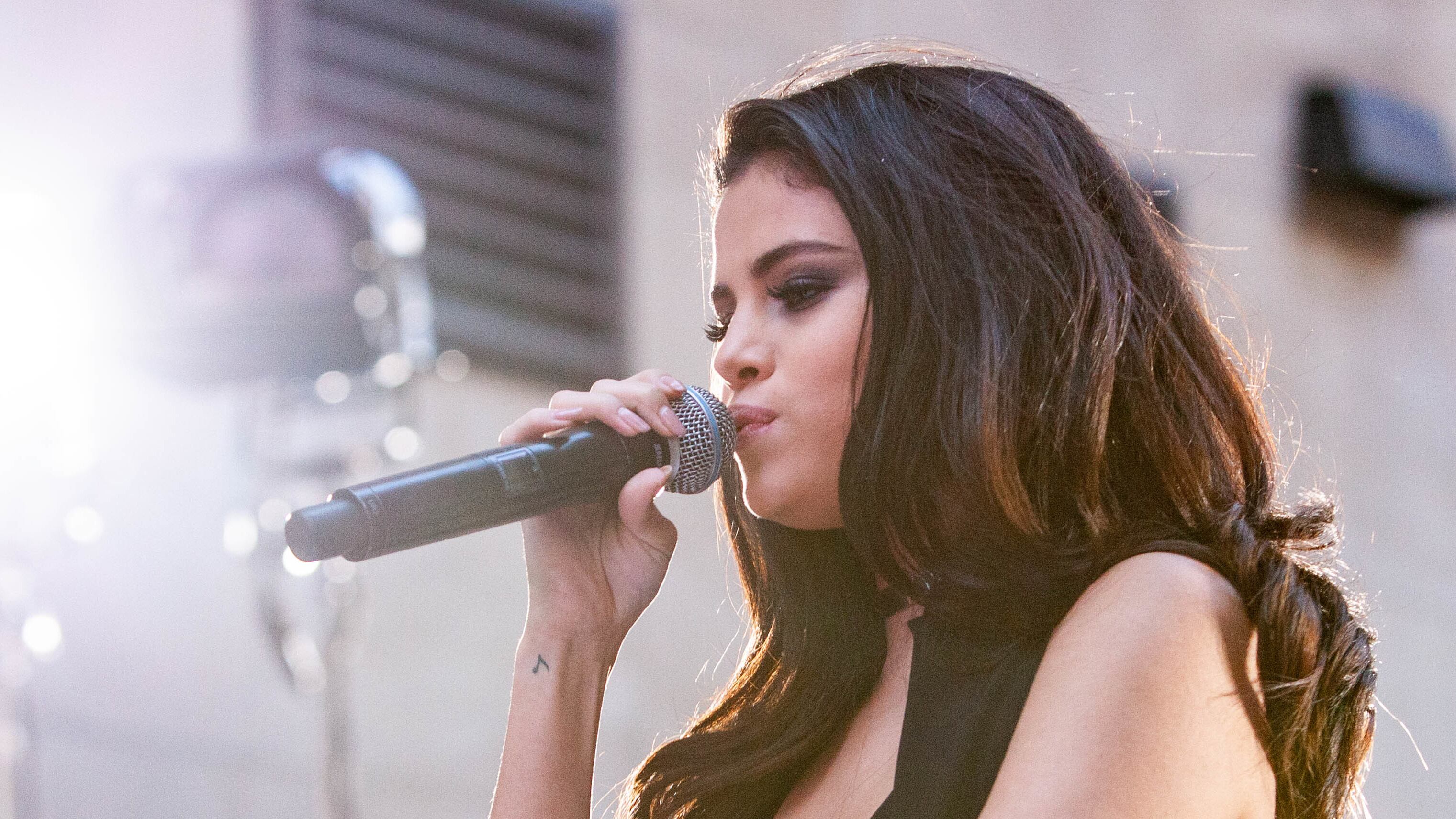 Selena Gomez onstage holding a microphone