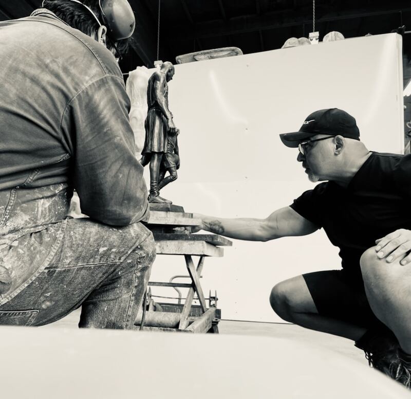 "A photo of Dan Medina beside his statue."