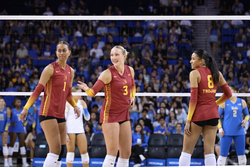 Faumuina (1) with Reese Messer (3) and Mia Tvrdy (8) on court at Pauley Pavilion; a blue-clad crowd can be seen in the background.