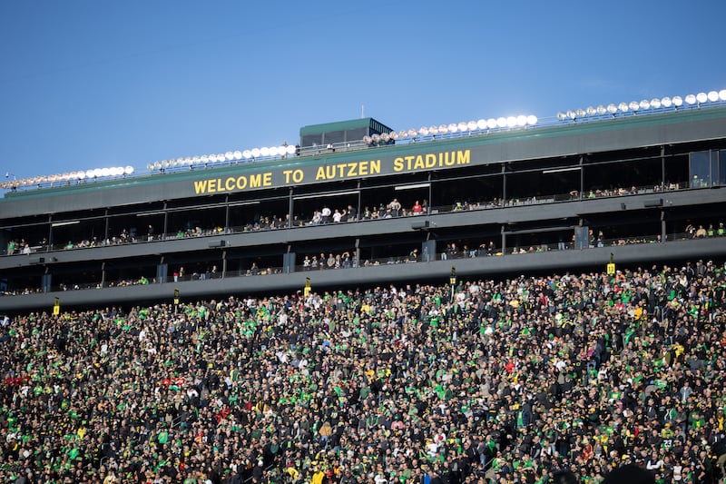 A wide shot of Autzen Stadium (headlined by a 'Welcome to Autzen Stadium' sign at the top) with stands filled with Oregon football fans clad in black, green and yellow.