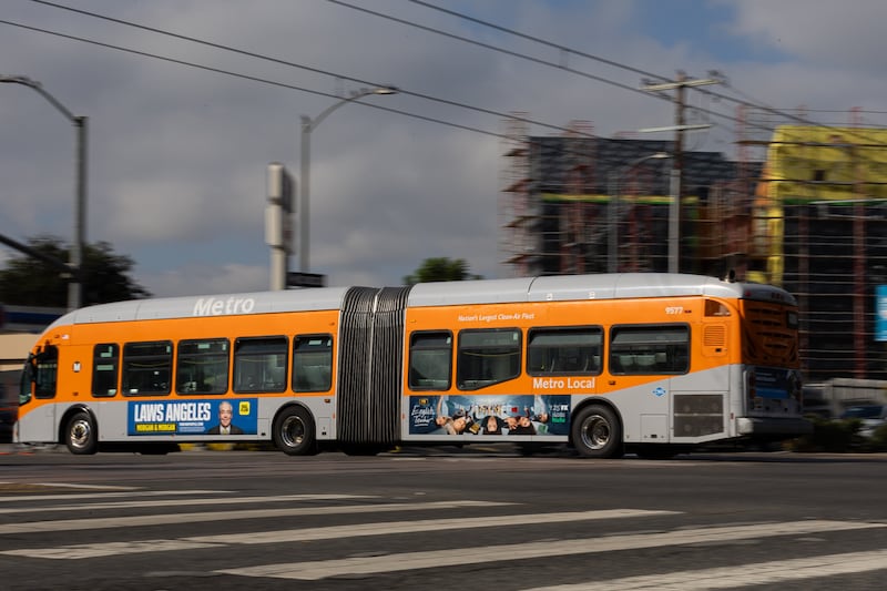 An orange bus drives down the street.