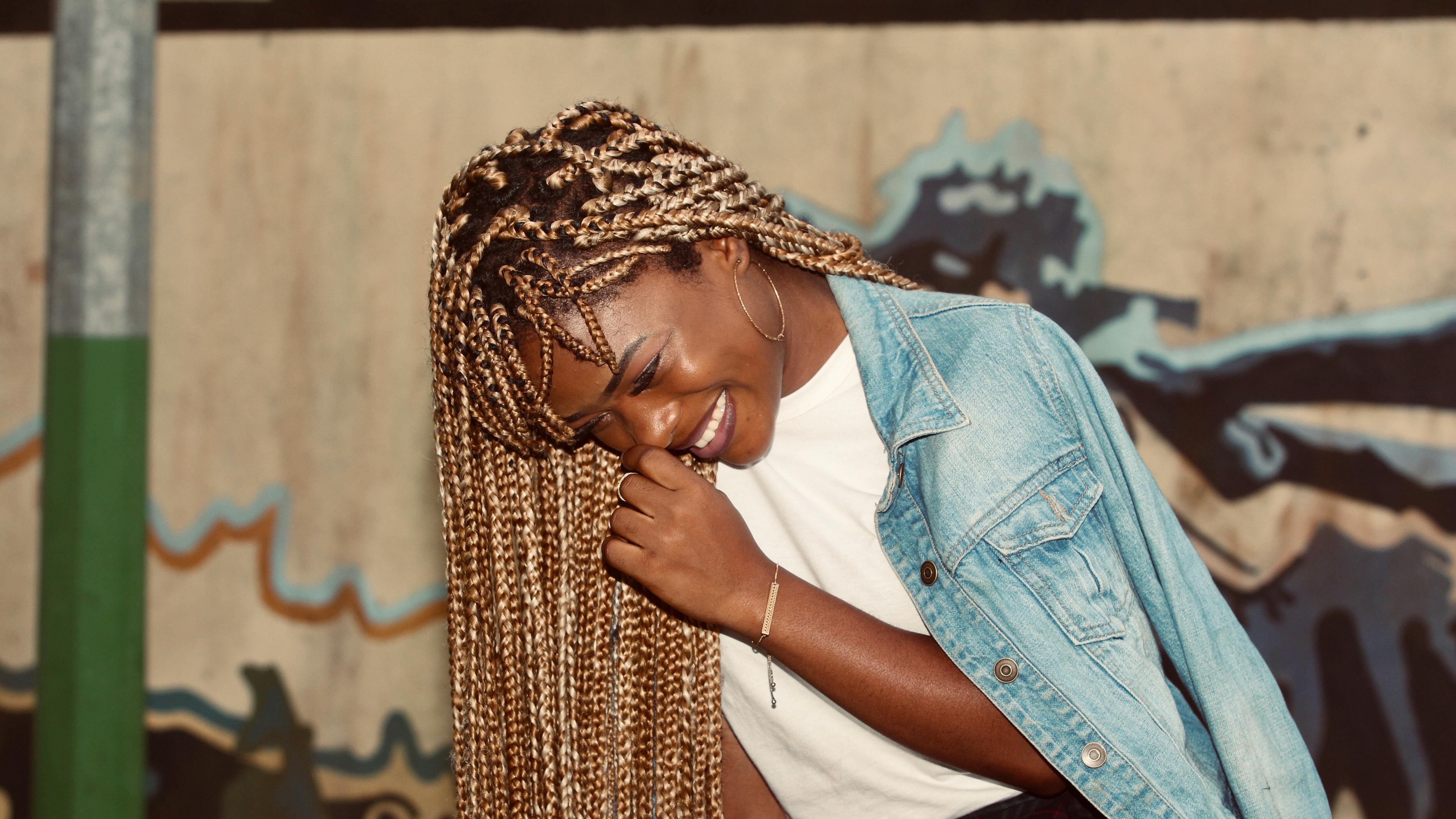A Black woman with braids laughs.