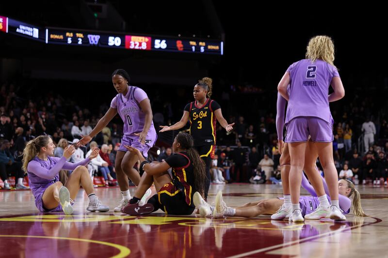 USC and UW players look around in confusion and help their fellow teammates (of which there are several) up from the floor. There appears to have been some kind of collision on the court.