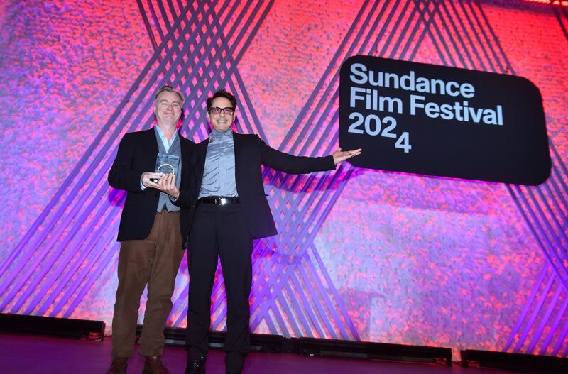 A photo of Nolan and Downey Jr. on stage posing in front of a sing that says the Sundance Film Festival 2024.