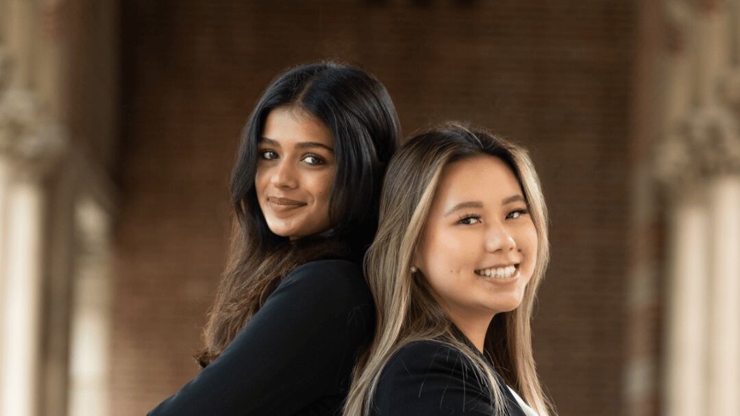 USG presidential candidates Divya Jakatdar and Michelle Lu pose back-to-back with their arms crossed.