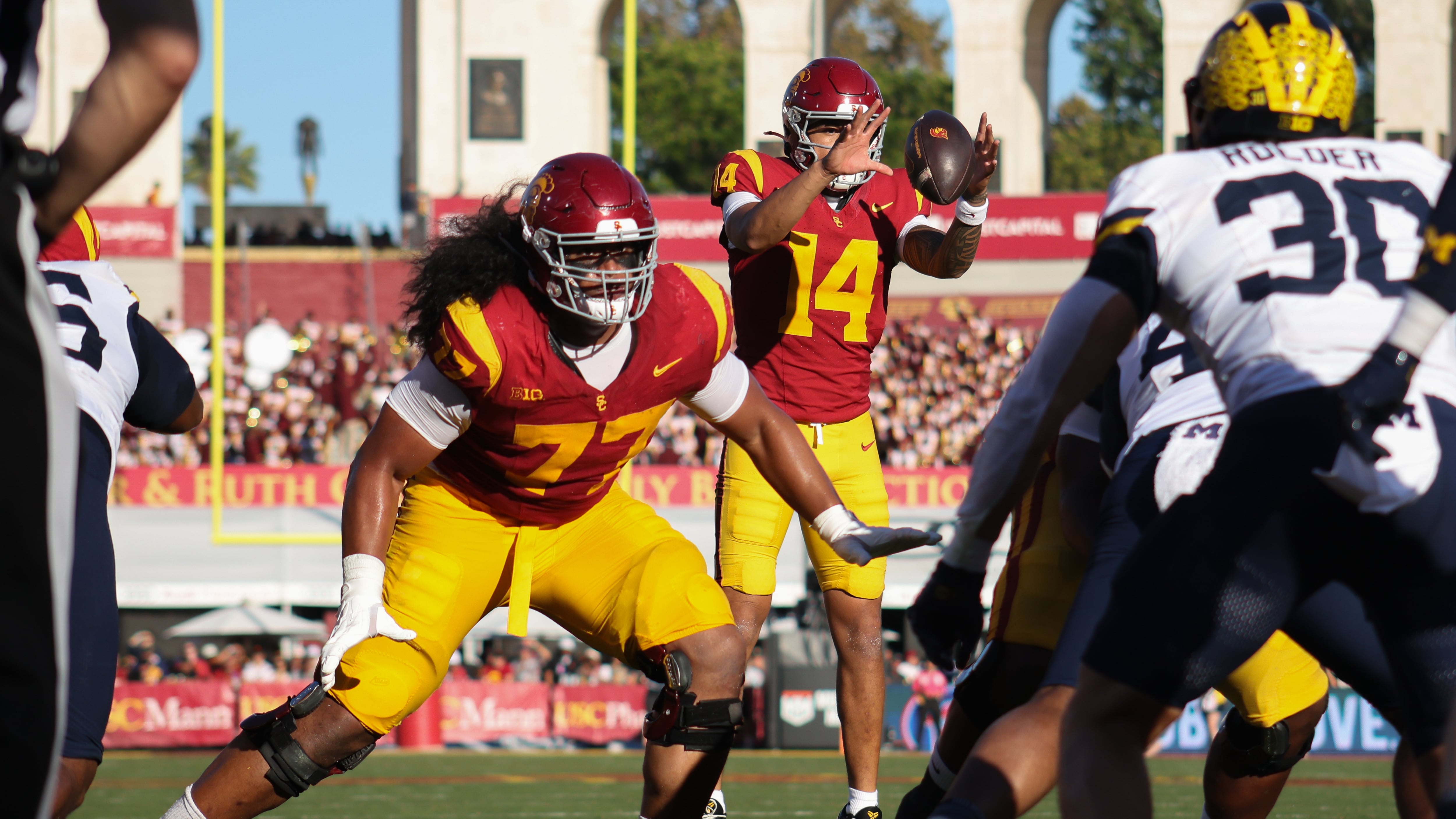 Photo of football player in red jersey and yellow pants blocking for his quarterback.