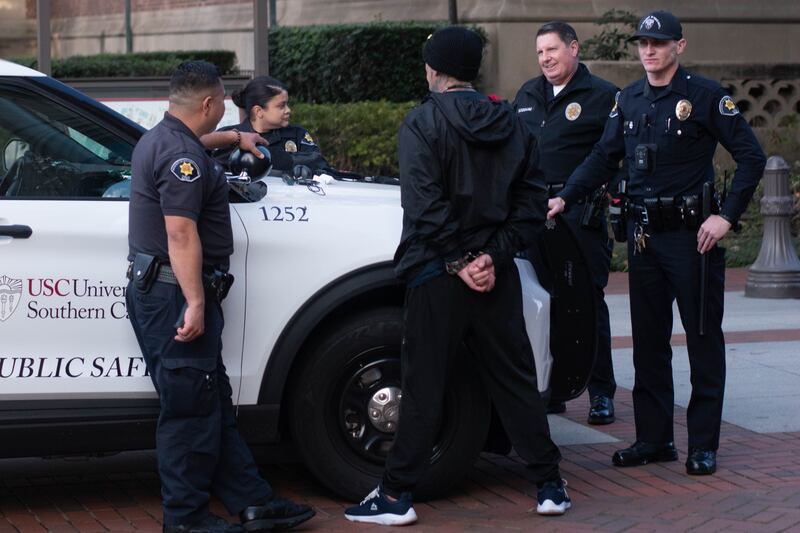 A photo of the suspected shoplifter handcuffed and surrounded by four officers.