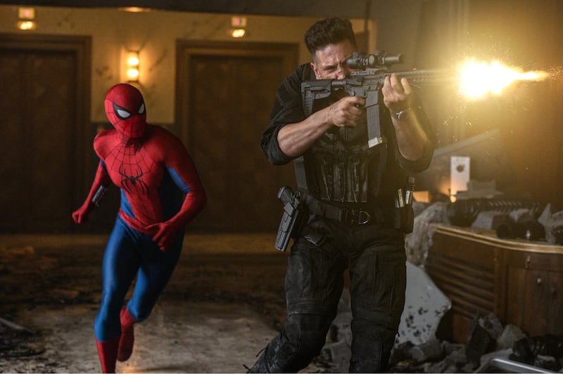Spider-Man suited up and the Punisher run through a building while the Punisher opens fire.