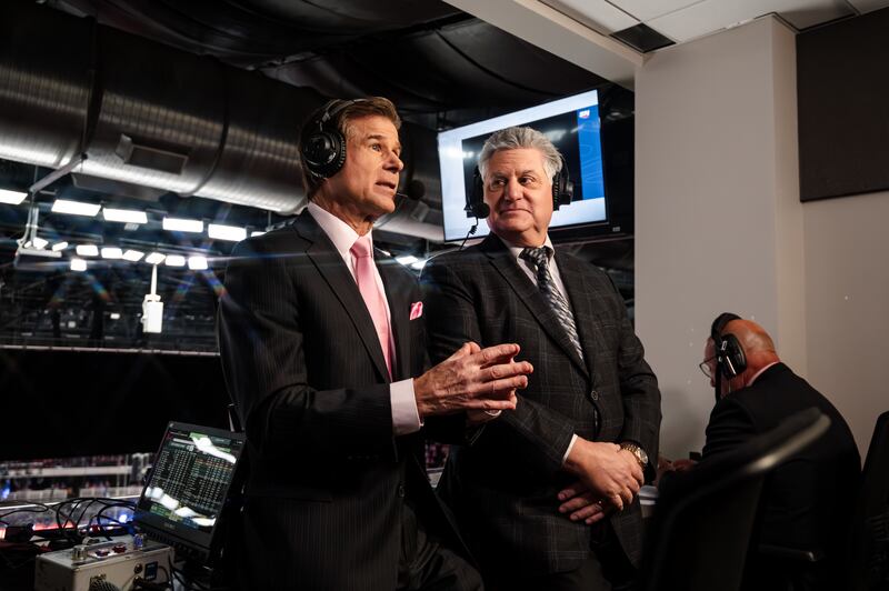 Jim Fox and Nick Nickson together in the press box. Both wear suits and headsets.