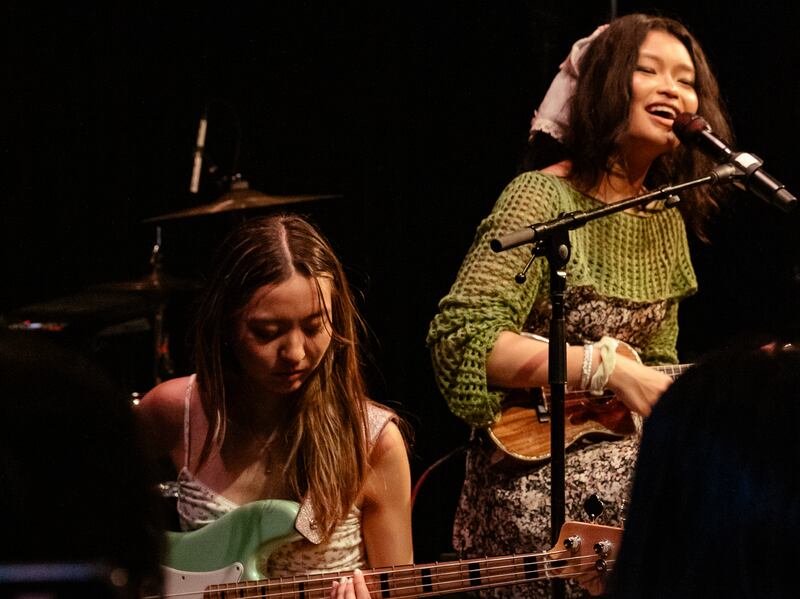Photo of a singer with a small guitar behind a guitarist