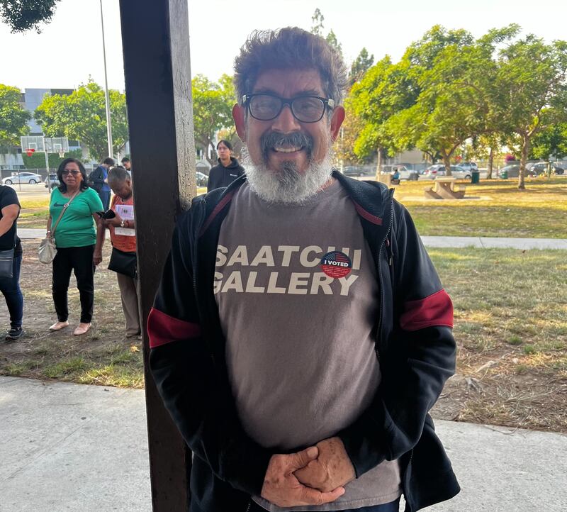 A man in a black and red hoodie standing outside.
